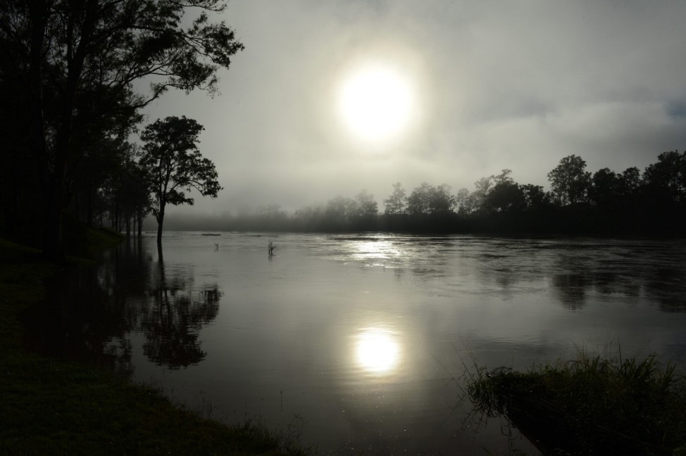 Early morning sun rises through the fog over the swollen Brisbane