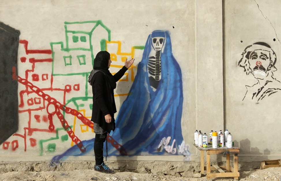 Afghan artist Malina Suliman paints graffiti on a wall in Kandahar city