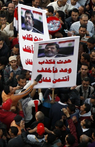 Protesters opposing Egyptian President Mohamed Mursi shout slogans and hit a poster of Mursi that reads 'If he speaks, he always lies' with shoes at Tahrir Square in Cairo