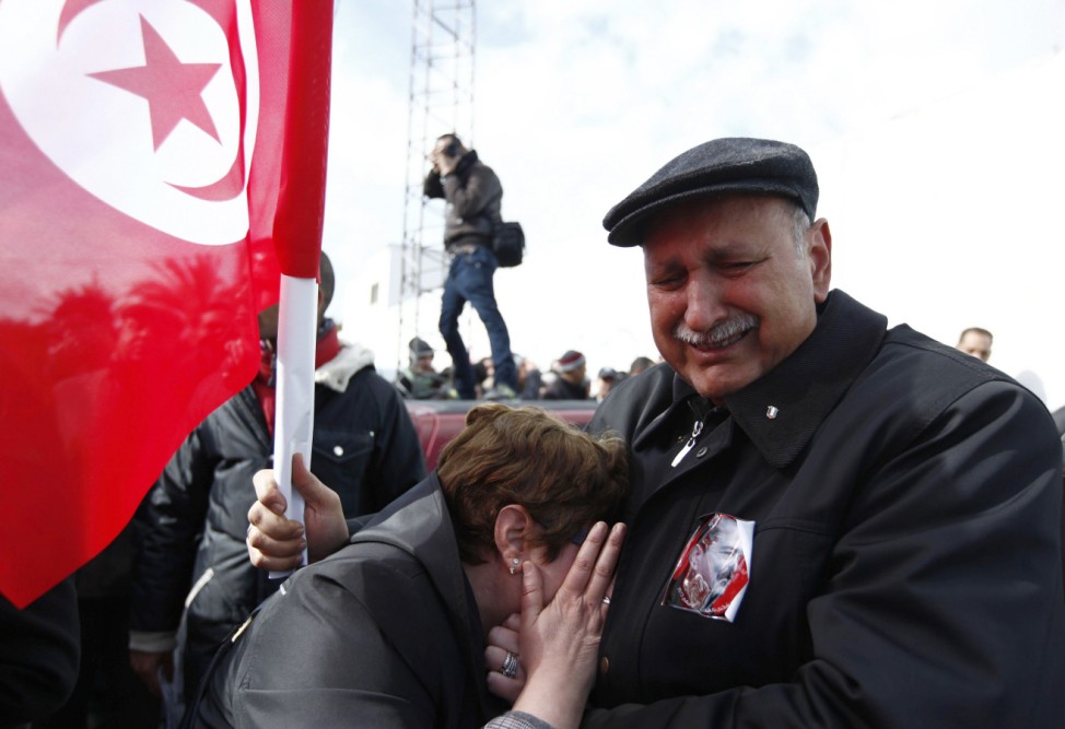 Couple mourns next to Tunisian flag during funeral procession for late secular opposition leader Belaid in Tunis