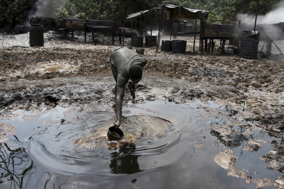 File photo shows a man collecting polluted water at an illegal oil refinery site near river Nun in Bayelsa