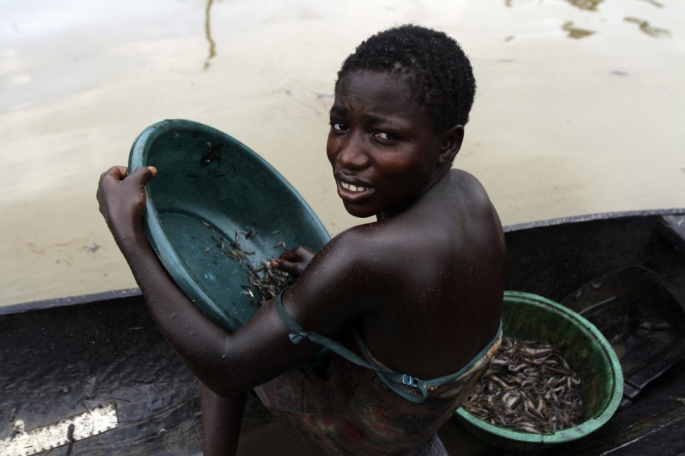 A girl coated in oil sits in a canoe as she sort crabs near the River Nun in Nigeria's oil state of Bayelsa