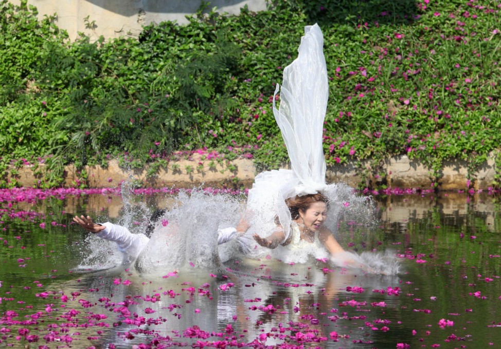 Thai groom Sopon Sapaotong and his bride Chutima Imsuntear jump in a pond during a wedding ceremony in Prachin Buri province