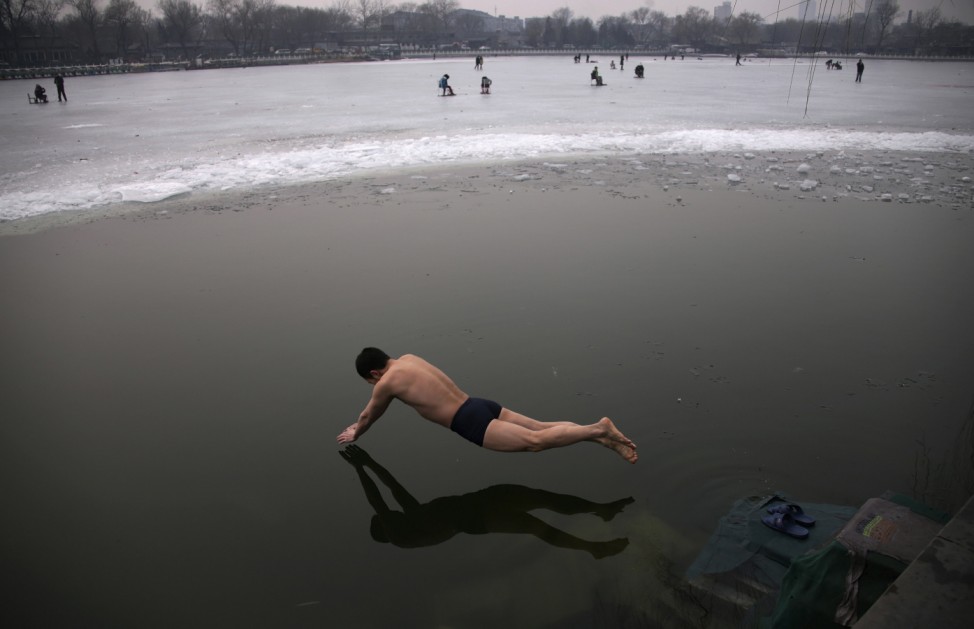 A swimmer dives into the icy water of the Houhai Lake in central Beijing