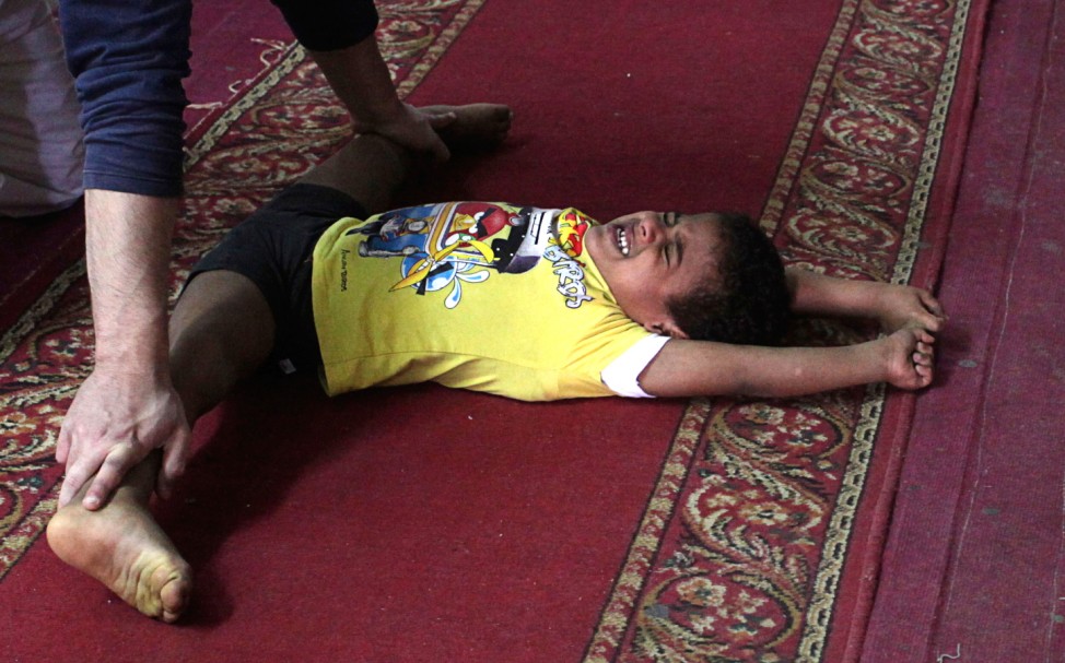 A coach helps a child stretch in a gymnastics hall in Alexandria