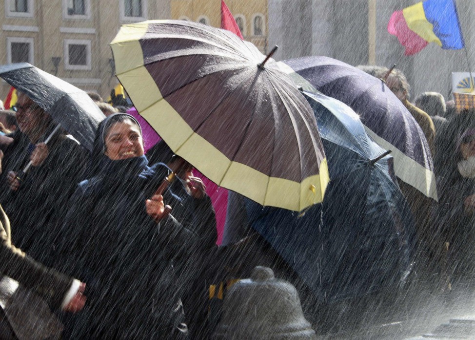 A nun holds an umbrella to protect herself from the spray of water from a fountain as she waits for Pope Benedict XVI to lead the Angelus in Saint Peter's Square at the Vatican
