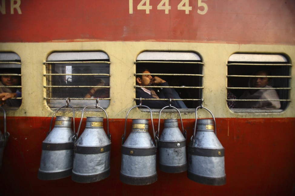 Empty milk containers hang from the window of a train in Uttar Pradesh