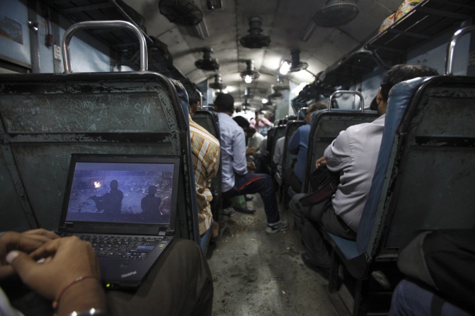 A man watches a film on his laptop as the train heads toward Agra from Delhi