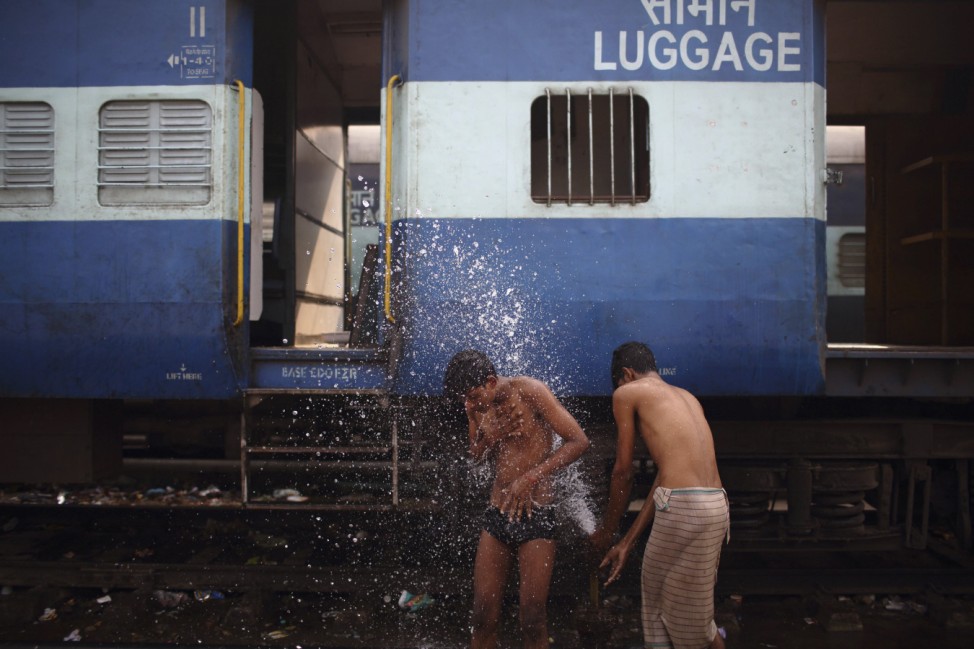 A boy washes using a pipe that supplies water to trains at Old Delhi Railway Station in Delhi