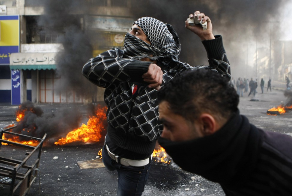A Palestinian protester throws stones during clashes with Israeli soldiers in Hebron following the funeral of Palestinian prisoner Jaradat
