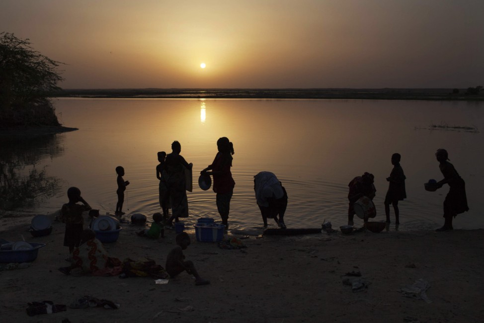 Women wash dishes at sunset in the Niger River in Gao