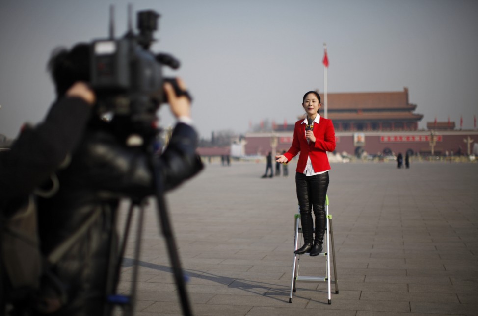 A journalist reports outside the Great Hall of the People at Tiananmen Square during the opening ceremony of the National People's Congress in Beijing