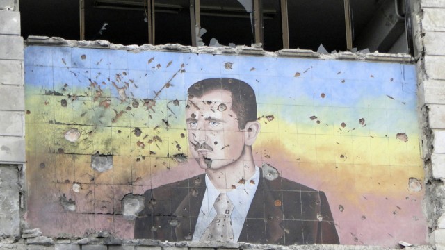 A picture of Syria's President Bashar al-Assad riddled with holes is seen on the facade of the police academy in Aleppo, after it was captured by Free Syrian Army fighters