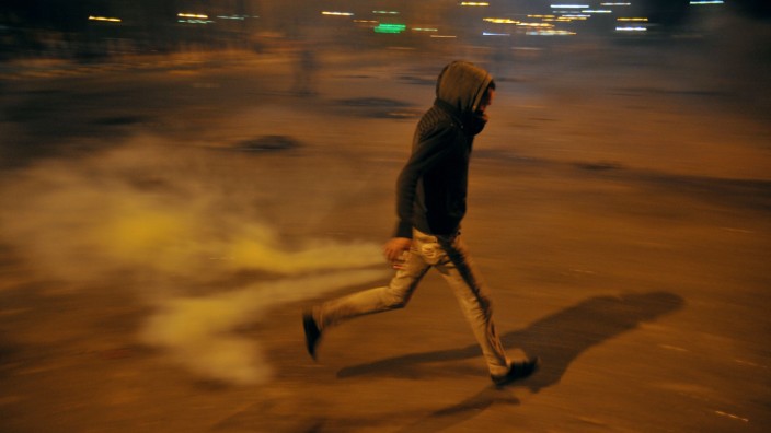 Krawalle in Ägypten: Ein Demonstrant in Port Said geht in Deckung vor der Polizei, die Tränengas gegen die Aufständischen einsetzt.