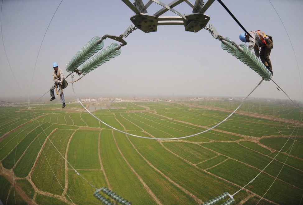 Electricians check the electricity pylon situated amid farmland in Chuzhou