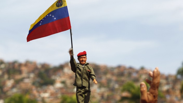 A supporter of Venezuela's late President Hugo Chavez holds up a doll of Chavez in Caracas
