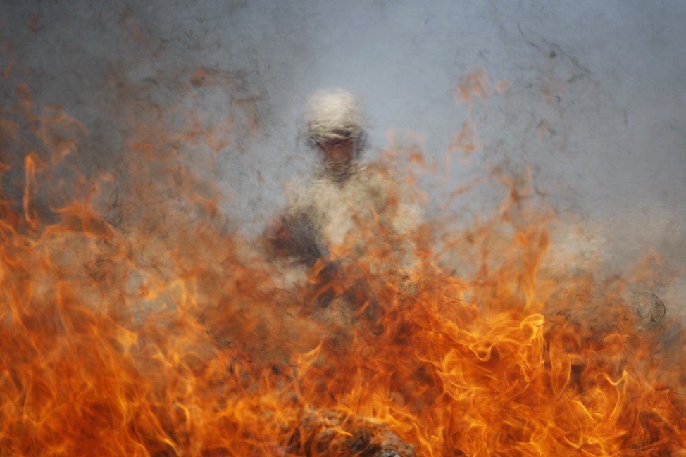 A soldier stands behind fire as marijuana and other drugs are being incinerated at a military base in Ciudad Juarez