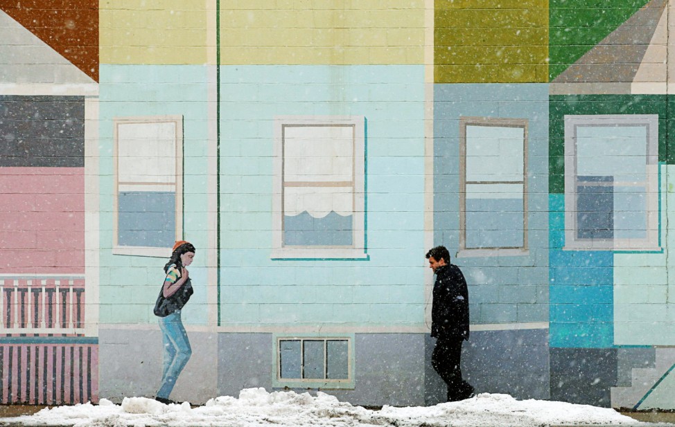 A pedestrian walks past a mural at the beginning of a winter storm in Somerville