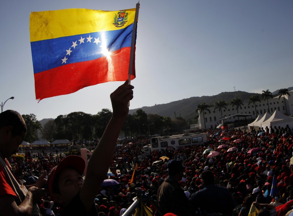 A supporter of Venezuela's late President Chavez holds up a Venezuelan flag as he waits to view his body lying in state in Caracas