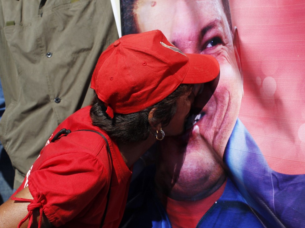 A supporter of Venezuela's late President Chavez kisses a portrait of him as she waits for a chance to view his body lying in state in Caracas