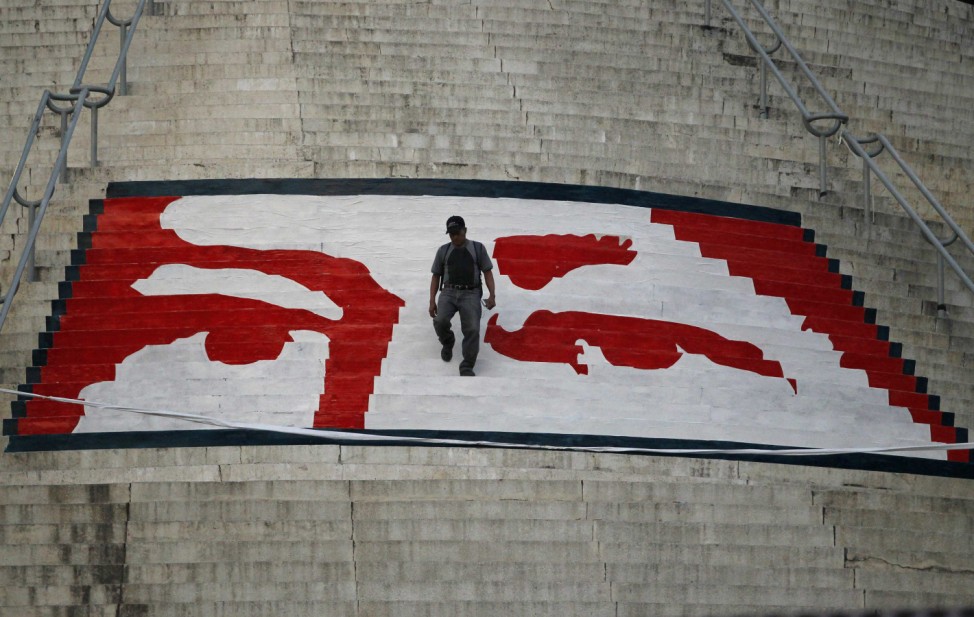 A man walks at the steps to a monument painted with the likeness of Venezuela's late President Hugo Chavez in Caracas