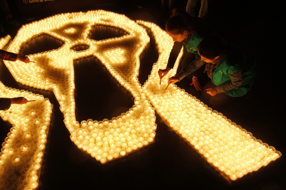 Greenpeace activists light candles to mourn victims of the Fukushima earthquake and tsunami in downtown Bucharest