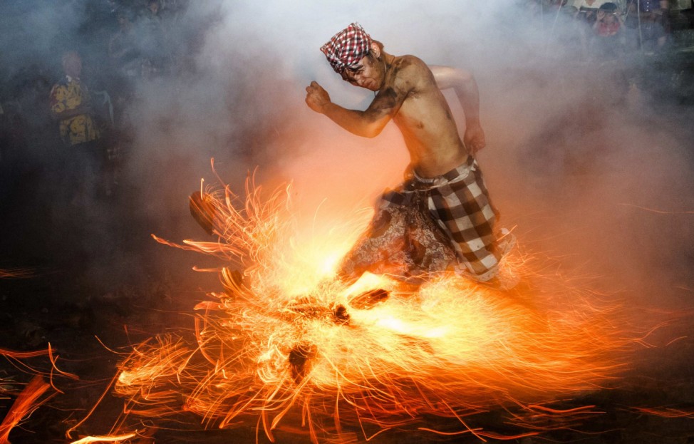 A Balinese man kicks up fire during the 'Perang Api' ritual ahead of Nyepi day, in Gianyar, Bali