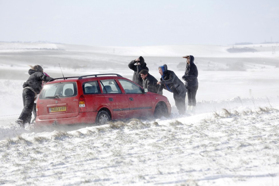 People try to move a car stuck in snow on the South Downs near Brighton