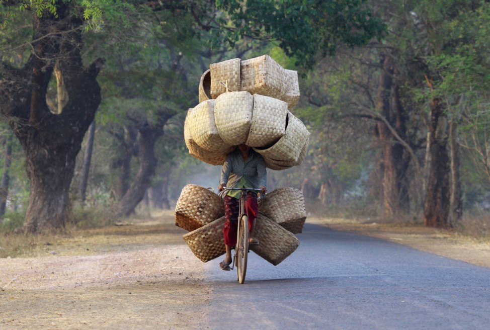 A woman cycles as she carries baskets to sell in a market near Lapdaung mountain in Sarlingyi township