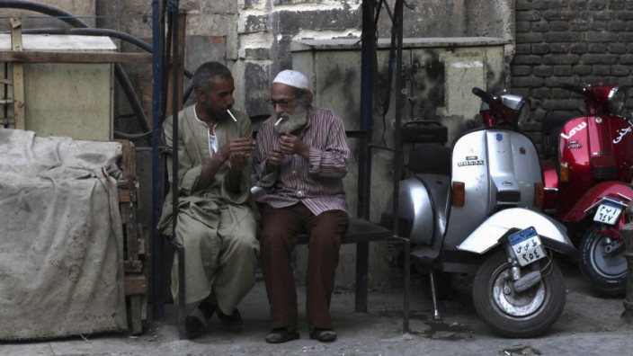 Men light cigarettes sitting on old public seats in an alley in old Cairo