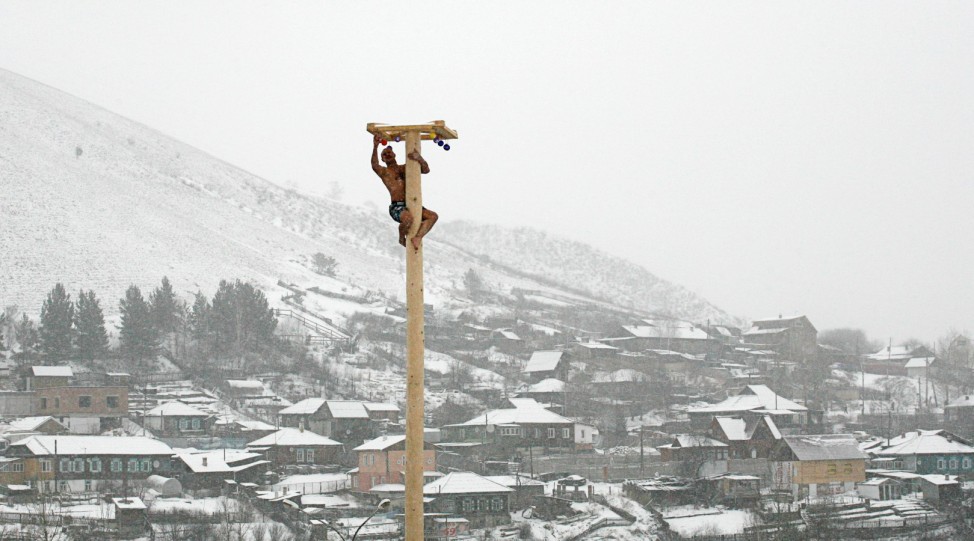 A man climbs up a smooth wooden column to win a contest during the celebrations of Maslenitsa, or Pancake Week, at the Bobrovy Log ski resort on the surburbs of Russia's Siberian city of Krasnoyarsk