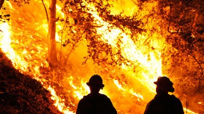 Kalifornien: Feuerwehrleute aus Los Angeles stehen vor einer Flammenwand, Tausende Hektar Land sind bereits verkohlt.