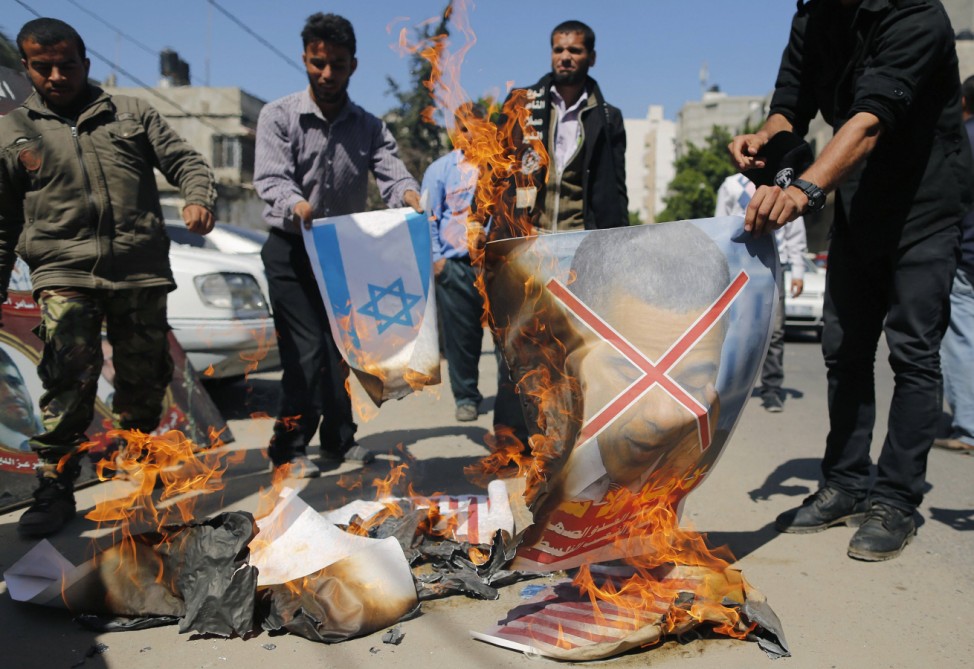 Palestinians burn pictures of U.S. President Obama and Israeli flag during a protest against Obama's visit, in Gaza