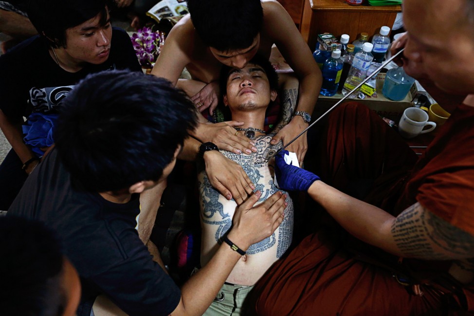 A Buddhist monk uses a traditional needle to tattoo the chest of Salut at Wat Bang Phra in Nakhon Pathom province