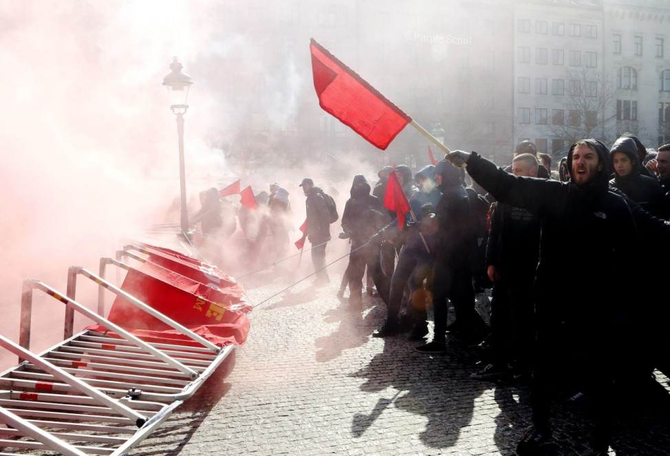 Counter-demonstrators throw smoke bombs and wave red flags against a protest by anti-Muslim organisation Swedish Defence League (SDL) in central Malmo