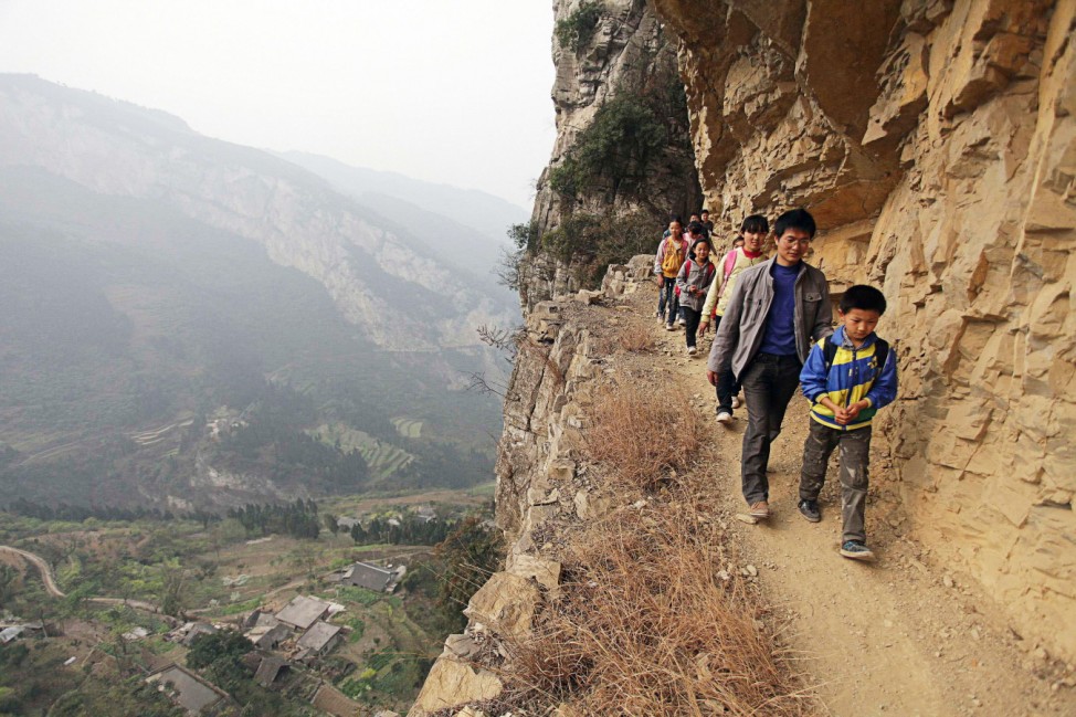 Xu Liangfan escorts students on a cliff path as they make their way to Banpo Primary School in Shengji county