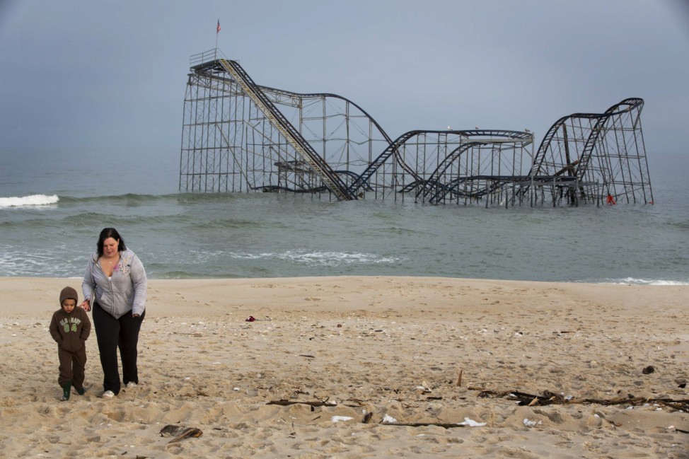 A woman and child walk away after looking at the remnants of the Jet Star roller coaster, almost five months after Superstorm Sandy, in Seaside Heights, New Jersey