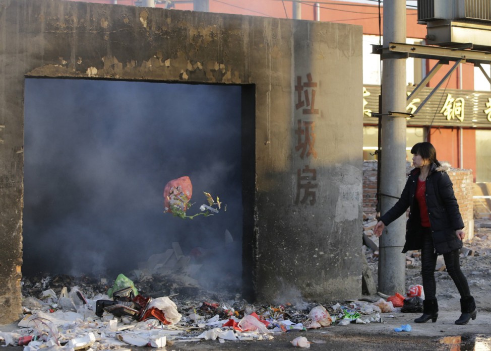 A resident throws a bag of household garbage into an open garbage room in Beijing