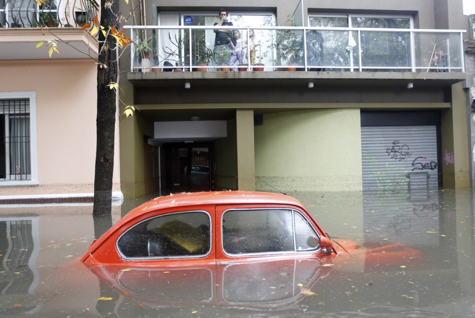Residents look at a submerged car in a flooded street after a rainstorm in Buenos Aires