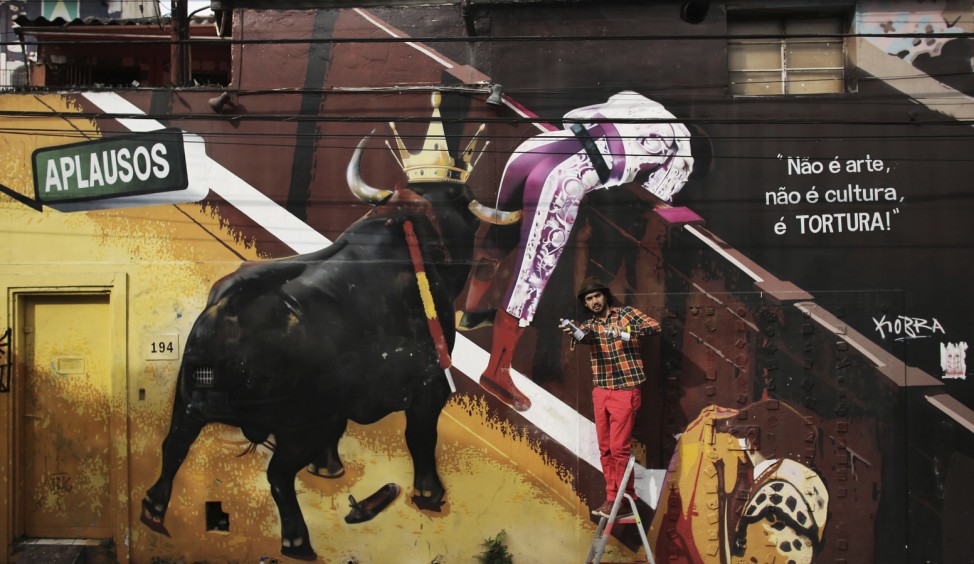 Brazilian artist Eduardo Kobra poses at the entrance of a house, decorated with an anti-bullfight artwork by him, at Vila Madalena neighborhood of Sao Paulo