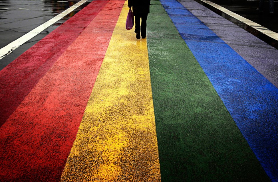 A pedestrian walks across a rainbow pedestrian crossing painted on Sydney's Oxford street