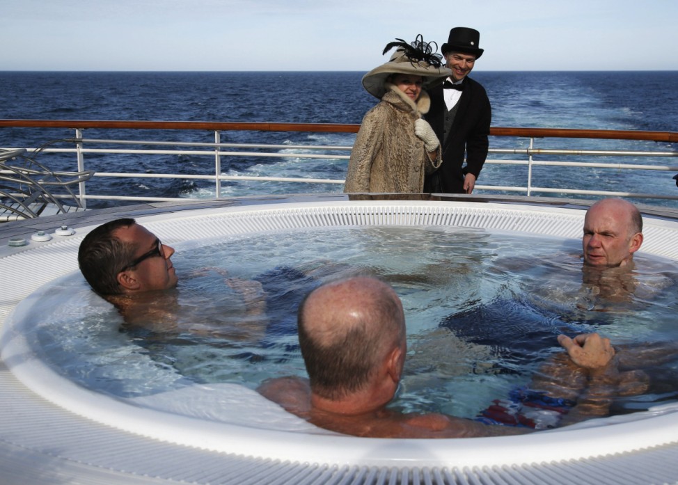 Canadians walk past fellow passengers in a hot tub on board the Titanic Memorial Cruise in the Atlantic Ocean off Cape Cod