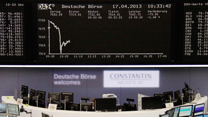 Traders work at their desks in front of the DAX board at the Frankfurt stock exchange