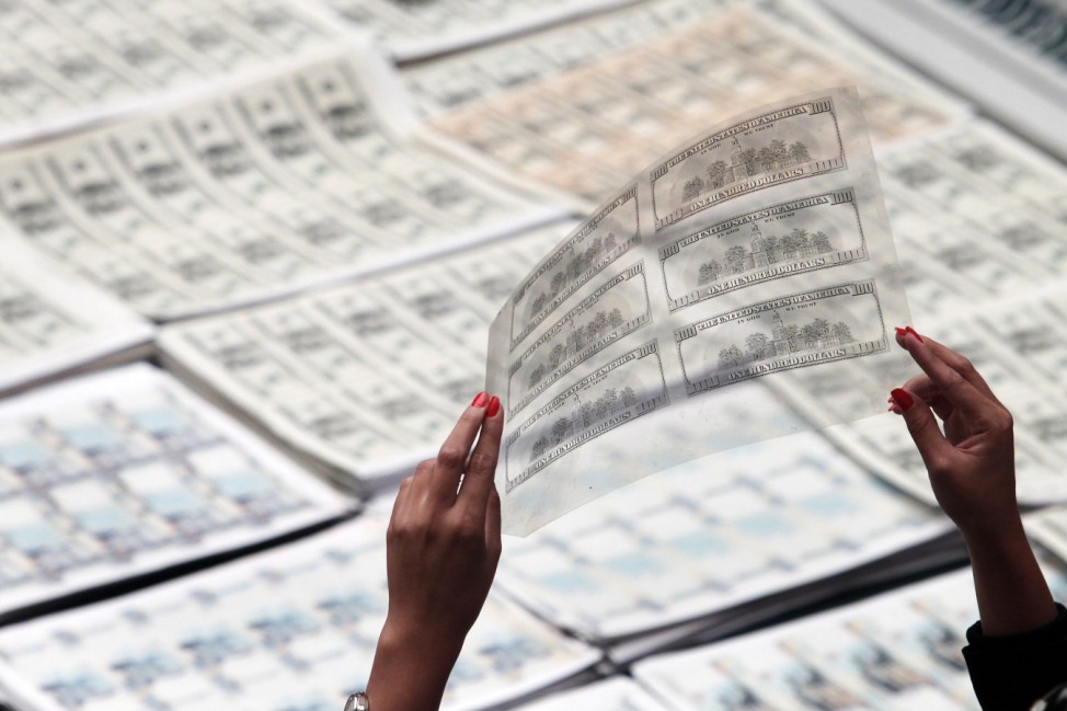 A police officer holds a film template for counterfeit U.S. dollar notes during a media conference in Lima