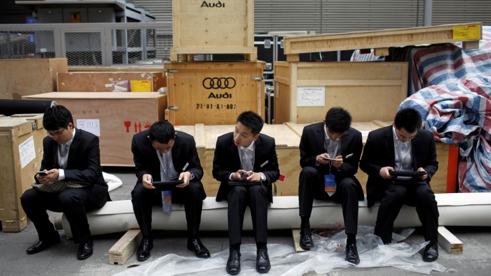 Men sit next to boxes of German carmaker Audi prior to the opening of the 15th Shanghai International Automobile Industry Exhibition