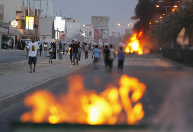 Protesters are seen on a street after setting fire to garbage containers during clashes with riot police in Budaiya, west of Manama