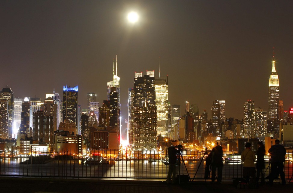 People photograph the full moon as it rises over New York City near 42nd Street, as seen across the Hudson River in Weehawken, New Jersey