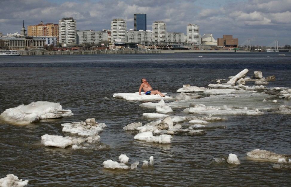Samsonov sunbathes as he sits on an ice floe on the Yenisei River in Krasnoyarsk