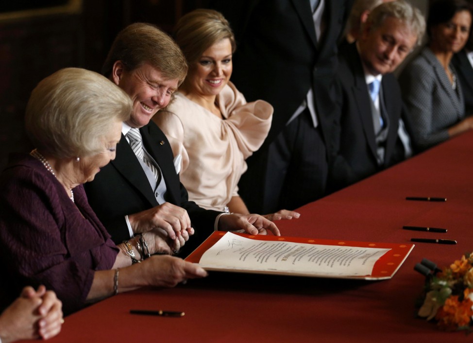 Queen Beatrix of the Netherlands passes the act of abdication to her son Crown Prince Willem-Alexander next to his wife Crown Princess Maxima during a ceremony at the Royal Palace in Amsterdam