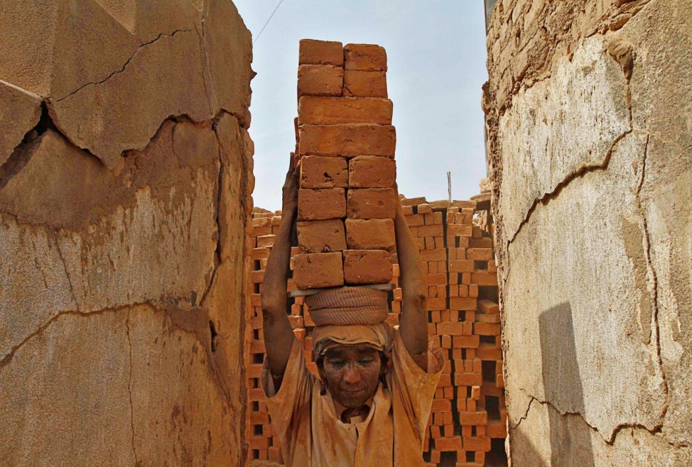 A female labourer carries bricks at a brick factory on the outskirts of the southern Indian city of Chennai